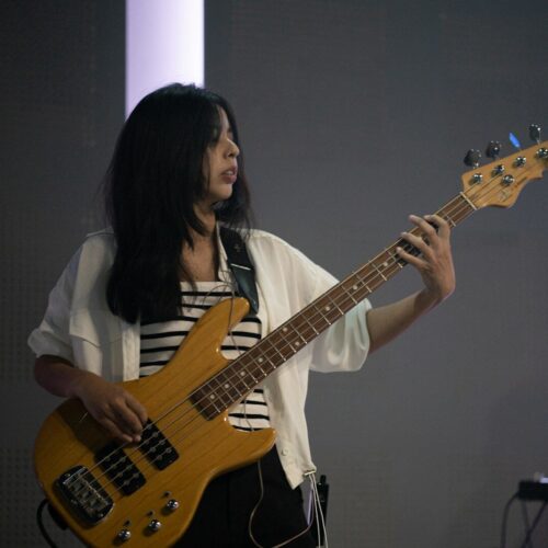 A woman playing a bass guitar on stage.
