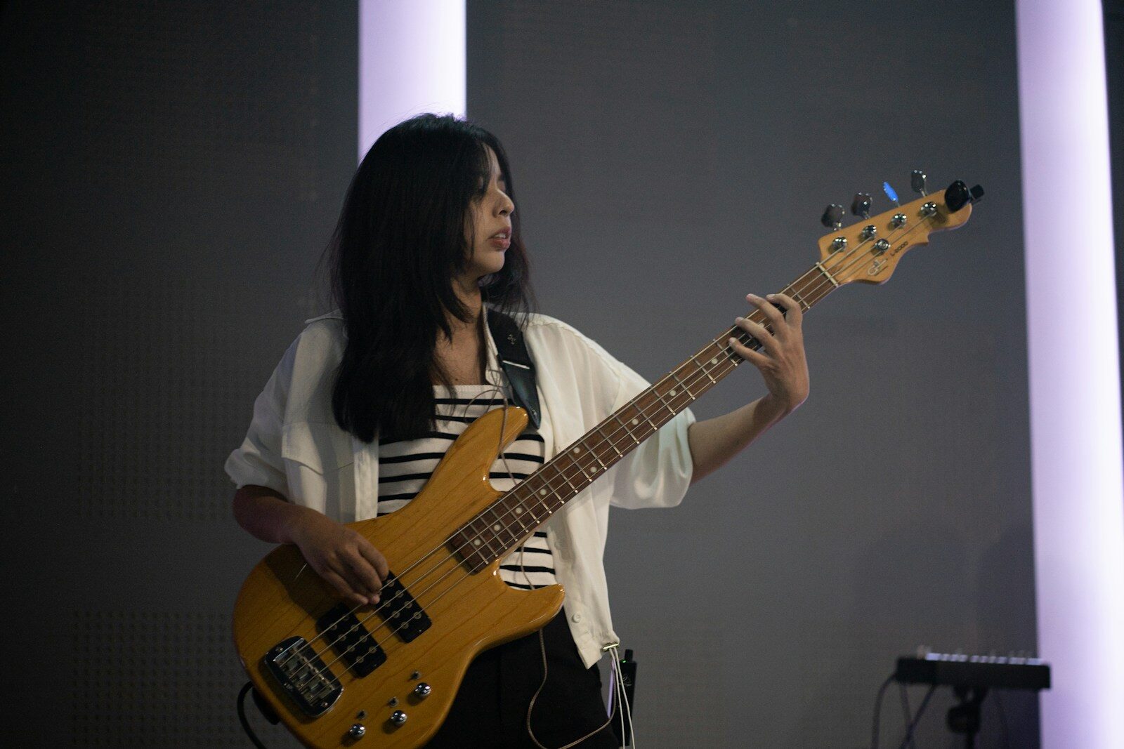 Photo by AMONWAT DUMKRUT A woman playing a bass guitar on stage.